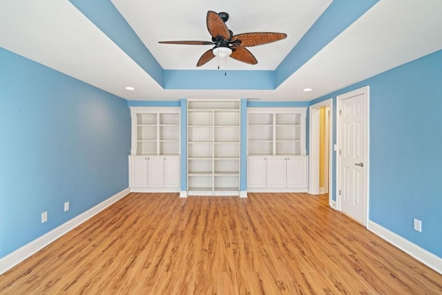 unfurnished bedroom with a tray ceiling, ceiling fan, and light hardwood / wood-style flooring