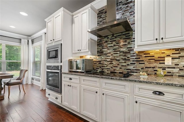161 Archstone Sq, Mcdonough, GA 30253 - kitchen featuring appliances with stainless steel finishes, wall chimney range hood, white cabinets, stone counters, and dark wood finished floors