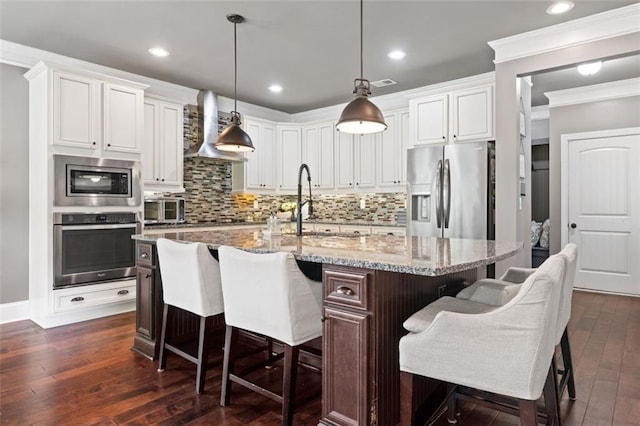 161 Archstone Sq, Mcdonough, GA 30253 - kitchen with appliances with stainless steel finishes, wall chimney exhaust hood, crown molding, a sink, and dark wood-style floors