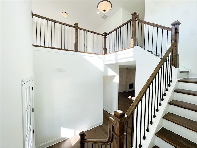 stairway featuring hardwood / wood-style flooring and a towering ceiling