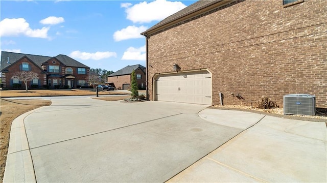 view of side of property featuring a garage, concrete driveway, brick siding, and central air condition unit