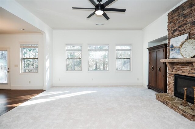 unfurnished living room featuring ceiling fan with notable chandelier, dark hardwood / wood-style flooring, a wealth of natural light, and a stone fireplace