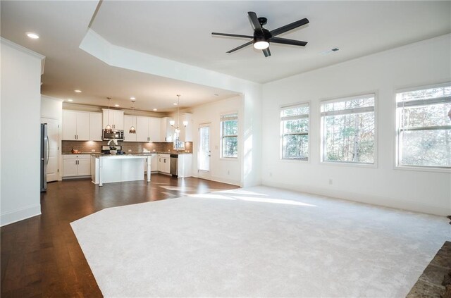 living room with dark hardwood / wood-style floors, a stone fireplace, and ceiling fan with notable chandelier