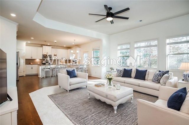 living room with dark wood-type flooring and ceiling fan with notable chandelier