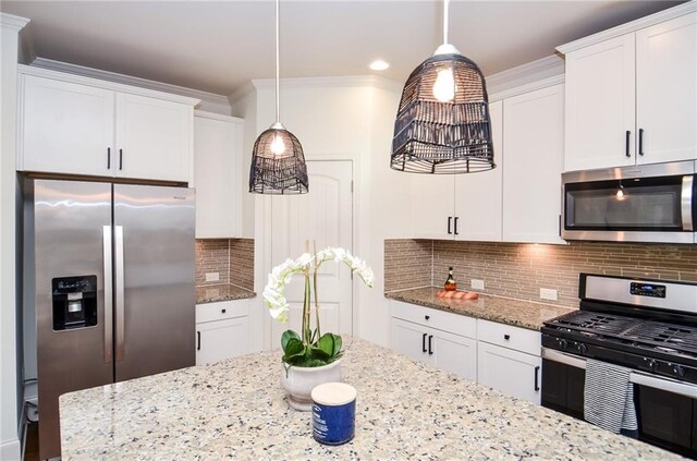 kitchen featuring white cabinets, appliances with stainless steel finishes, pendant lighting, and decorative backsplash