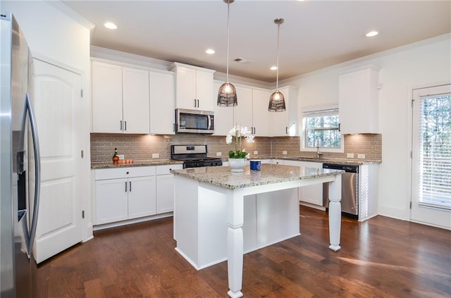 kitchen featuring appliances with stainless steel finishes, hanging light fixtures, white cabinetry, and a center island