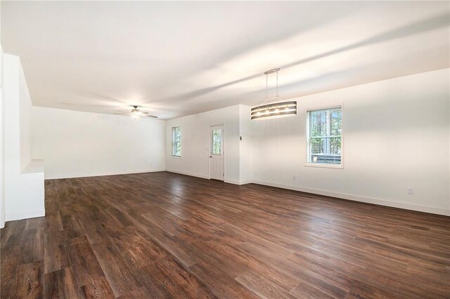 unfurnished room featuring ceiling fan, a healthy amount of sunlight, and dark hardwood / wood-style floors