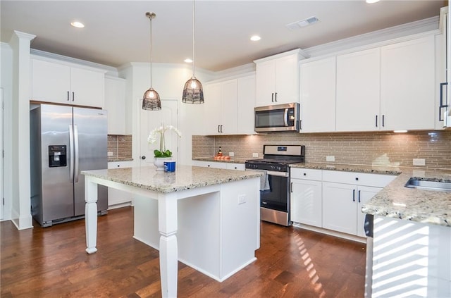 kitchen with appliances with stainless steel finishes, white cabinets, and decorative light fixtures