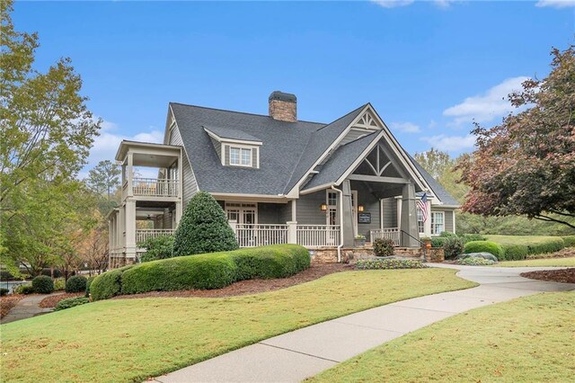 craftsman-style house featuring a balcony and a front lawn