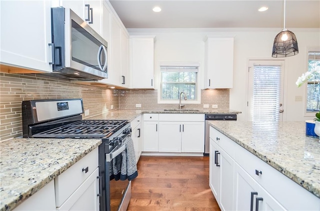 kitchen featuring hanging light fixtures, stainless steel appliances, decorative backsplash, white cabinetry, and sink