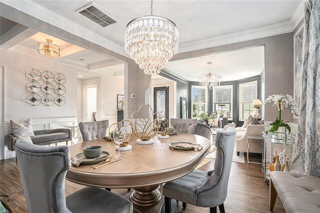 dining space with an inviting chandelier, ornamental molding, and hardwood / wood-style flooring