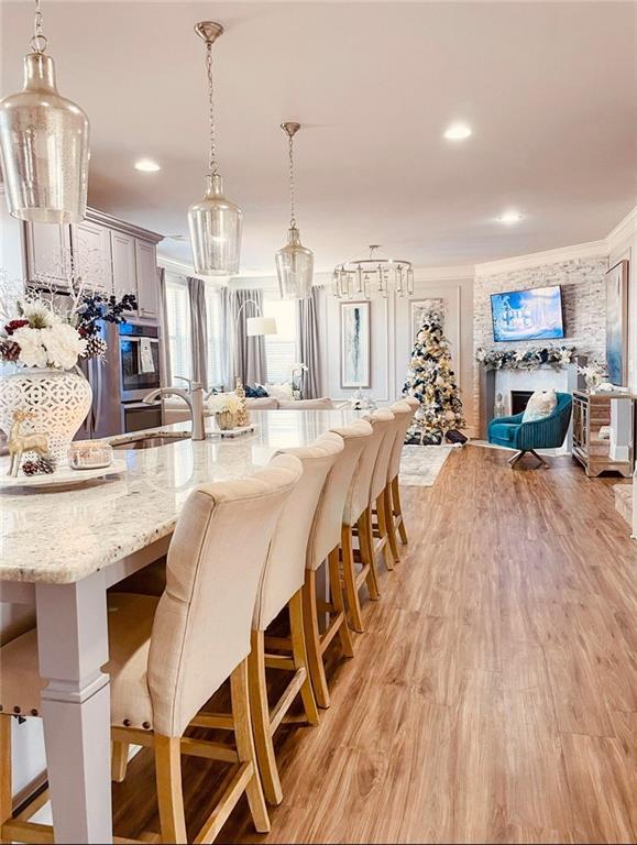 kitchen with a kitchen breakfast bar, light hardwood / wood-style floors, crown molding, and hanging light fixtures