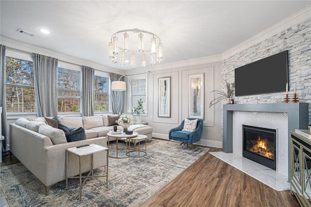 living room with hardwood / wood-style floors, a large fireplace, ornamental molding, and a wealth of natural light