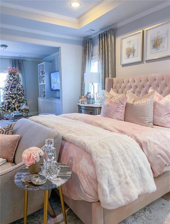 carpeted bedroom featuring a raised ceiling, ornamental molding, and multiple windows