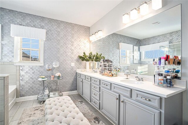 bathroom with a bathtub, a healthy amount of sunlight, tile walls, and vanity