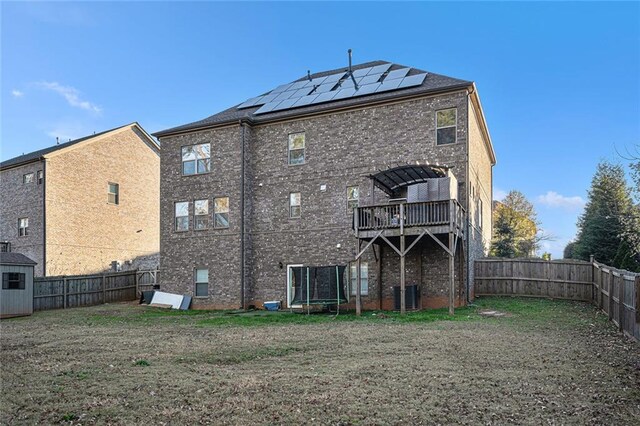 back of house with solar panels, a balcony, a storage shed, and central AC