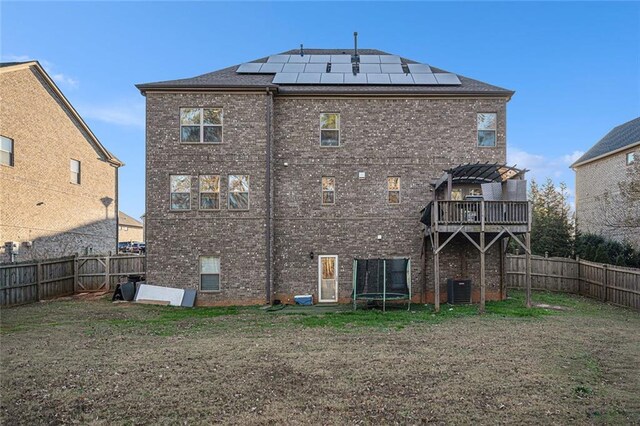 back of house with central AC unit, solar panels, a balcony, and a pergola