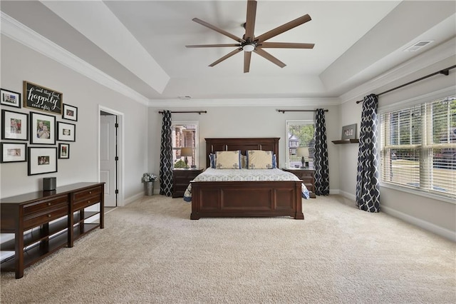 bedroom with a raised ceiling, light colored carpet, and multiple windows