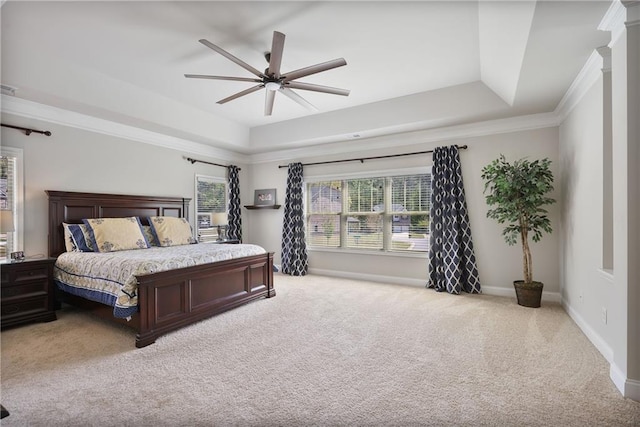 carpeted bedroom with a tray ceiling, baseboards, crown molding, and ceiling fan