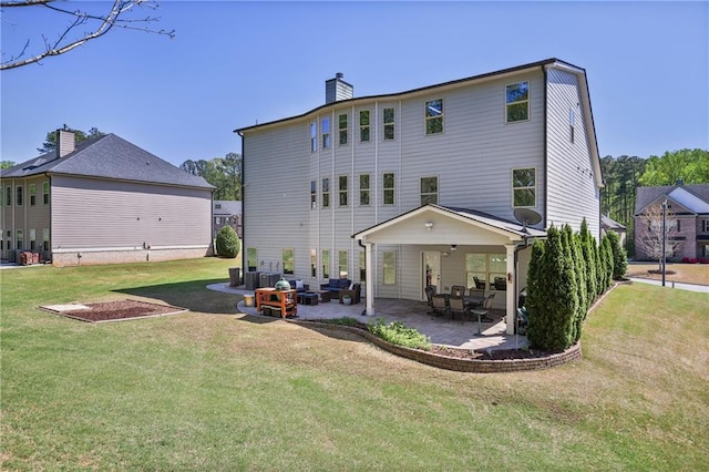 rear view of house featuring a chimney, a lawn, and a patio area