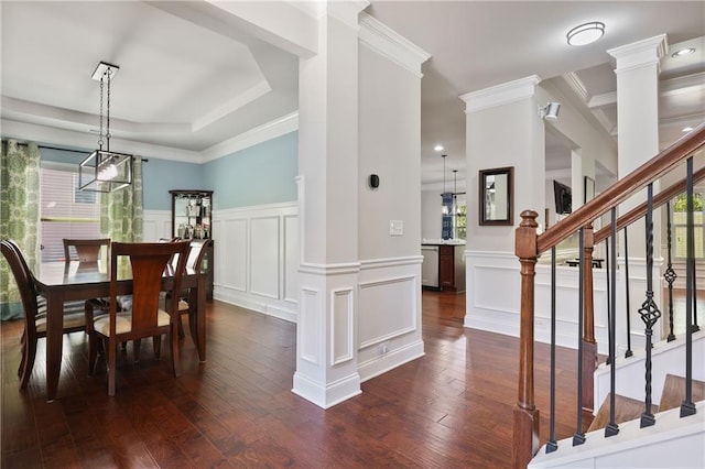 dining room featuring crown molding, dark wood-type flooring, stairway, a decorative wall, and a wainscoted wall