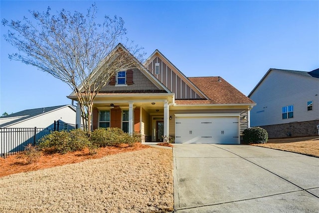 craftsman-style home with fence, driveway, stone siding, an attached garage, and a ceiling fan