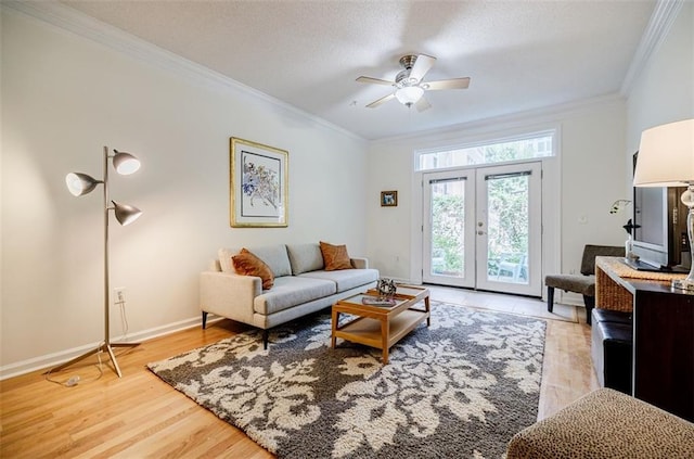 living area with a ceiling fan, baseboards, french doors, ornamental molding, and light wood-type flooring