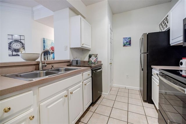 kitchen featuring light tile patterned floors, a sink, white cabinetry, ornamental molding, and appliances with stainless steel finishes