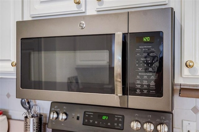 details featuring wall oven, stainless steel microwave, and white cabinets