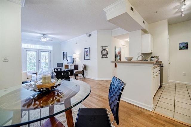 dining area featuring baseboards, light wood-style flooring, visible vents, and crown molding