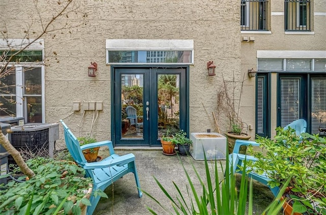 property entrance with french doors, central AC unit, and stucco siding