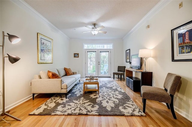 living area with baseboards, wood finished floors, crown molding, and french doors