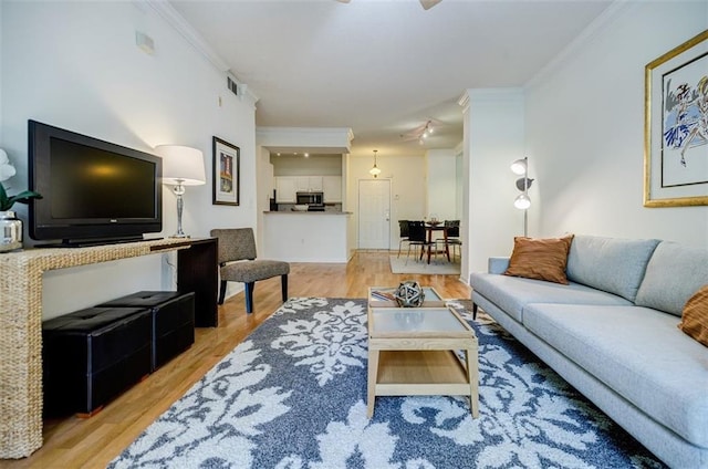 living area with ornamental molding, visible vents, and light wood-style floors