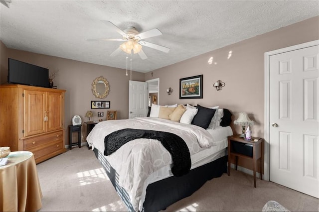 bedroom with a ceiling fan, light carpet, and a textured ceiling