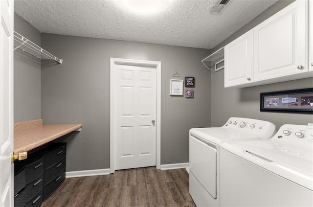 washroom with cabinet space, baseboards, dark wood-type flooring, a textured ceiling, and washer and dryer