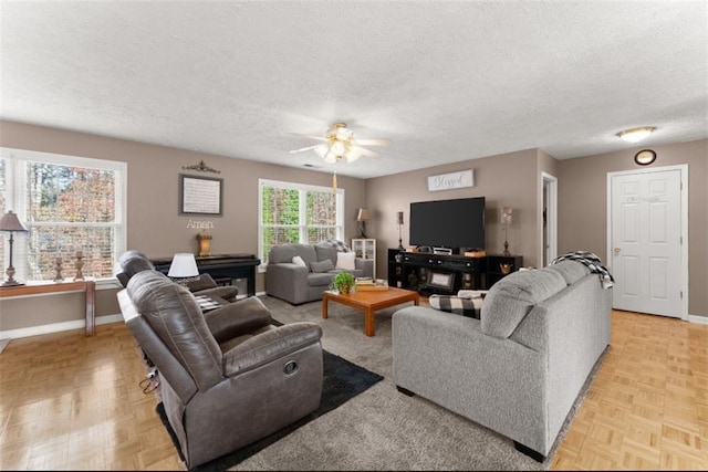 living room with ceiling fan, baseboards, and a textured ceiling