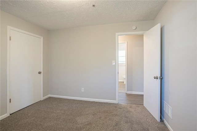 empty room featuring a textured ceiling and carpet floors