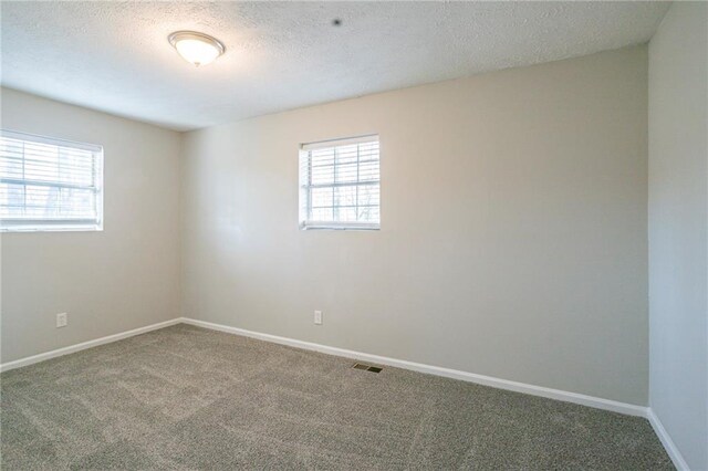 carpeted spare room with a textured ceiling