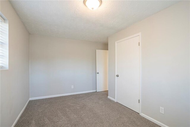 spare room featuring carpet flooring and a textured ceiling