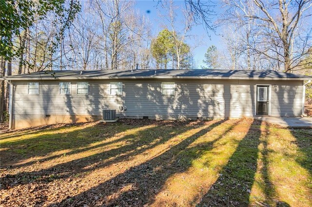 rear view of property featuring central AC unit, a patio area, and a lawn