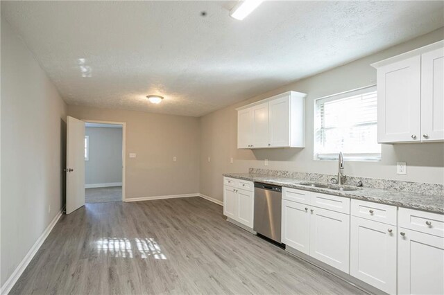 kitchen featuring light stone countertops, stainless steel dishwasher, a textured ceiling, sink, and white cabinetry