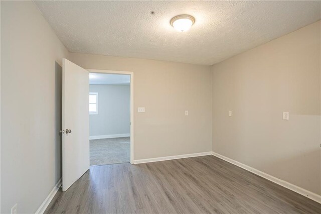 spare room featuring wood-type flooring and a textured ceiling