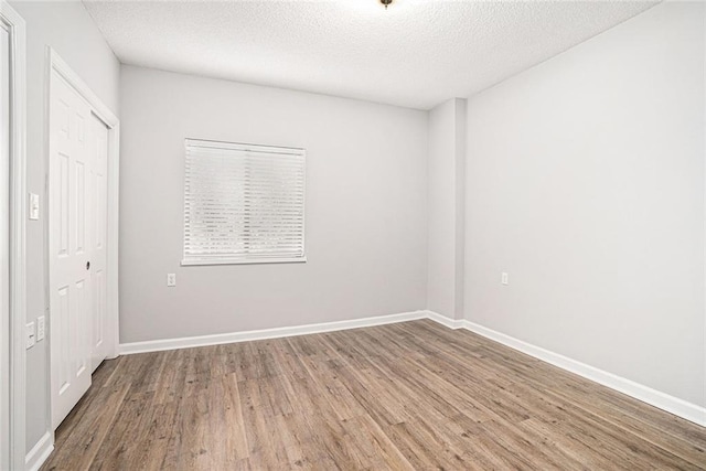 1800 Clairmont Lk Unit 412, Decatur, GA 30033 - unfurnished bedroom featuring wood finished floors, a textured ceiling, a closet, and baseboards