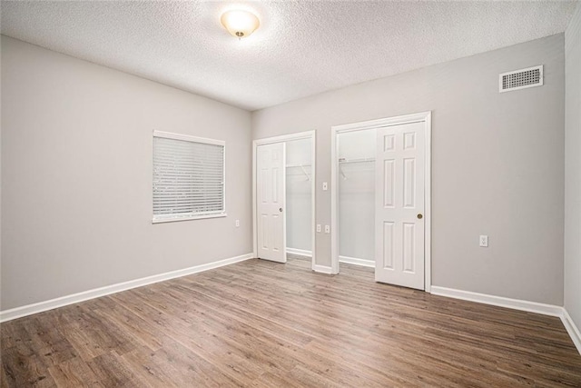 1800 Clairmont Lk Unit 412, Decatur, GA 30033 - unfurnished bedroom featuring wood finished floors, multiple closets, a textured ceiling, and baseboards