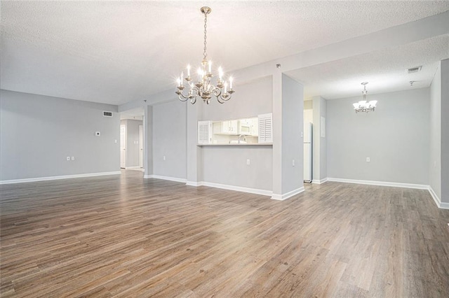 1800 Clairmont Lk Unit 412, Decatur, GA 30033 - unfurnished living room featuring a chandelier, wood finished floors, a textured ceiling, and baseboards