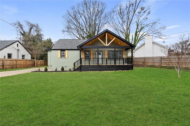 rear view of property with brick siding, a lawn, and fence