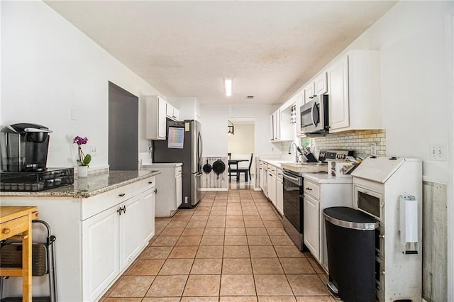 7341 Raleigh Way, Bethlehem, GA 30620 - kitchen featuring appliances with stainless steel finishes, white cabinets, light tile patterned floors, backsplash, and a textured ceiling