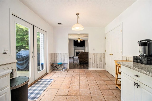 7341 Raleigh Way, Bethlehem, GA 30620 - kitchen featuring a wainscoted wall, ceiling fan, a fireplace, white cabinetry, and hanging light fixtures