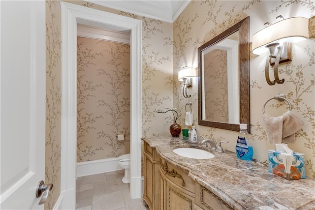 bathroom with toilet, vanity, baseboards, wallpapered walls, and crown molding