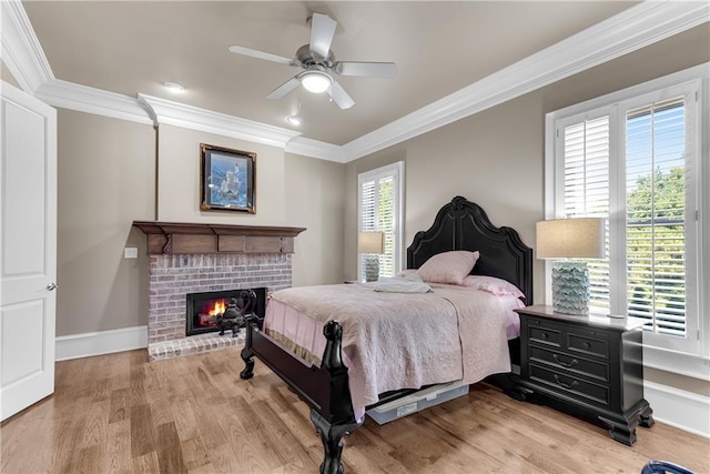 bedroom featuring ceiling fan, a fireplace, light hardwood / wood-style floors, and ornamental molding